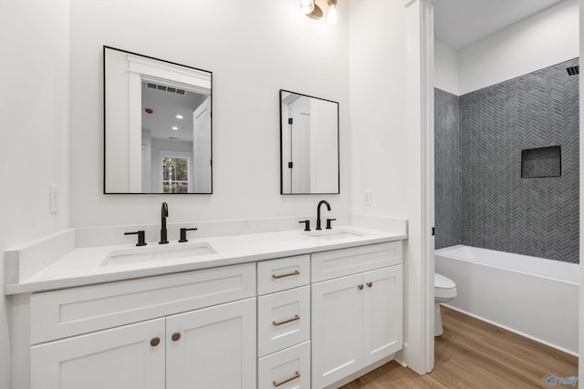 full bathroom with vanity, toilet, hardwood / wood-style flooring, and tiled shower / bath