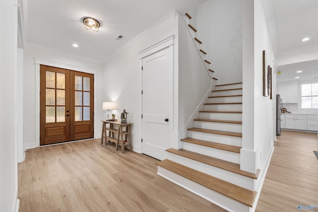 foyer entrance featuring french doors, light hardwood / wood-style flooring, and crown molding