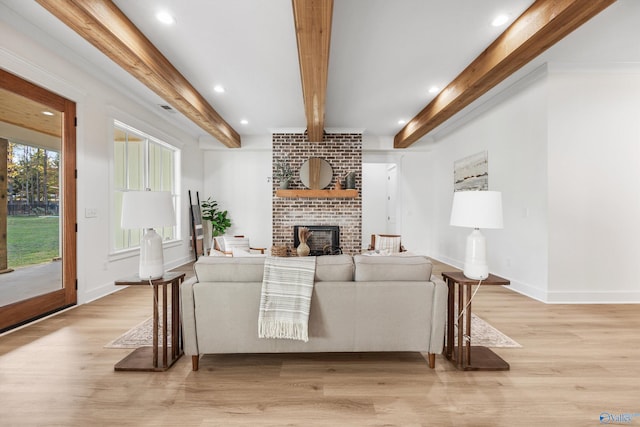 living room featuring light hardwood / wood-style floors, crown molding, beam ceiling, and a fireplace