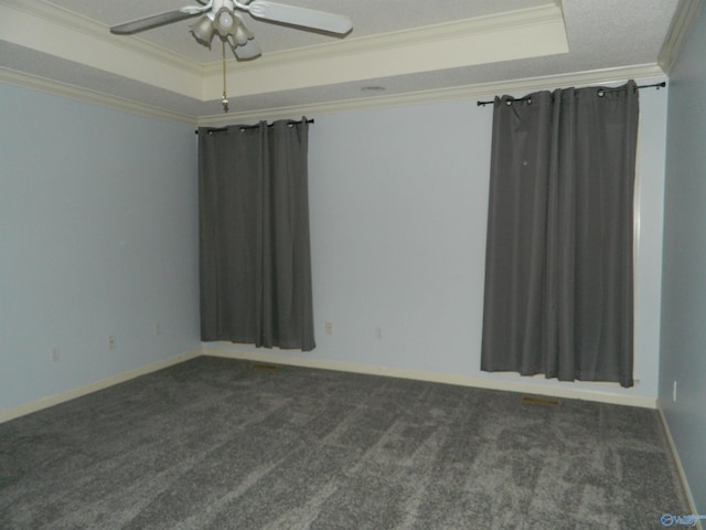 spare room featuring a ceiling fan, a raised ceiling, crown molding, and dark colored carpet