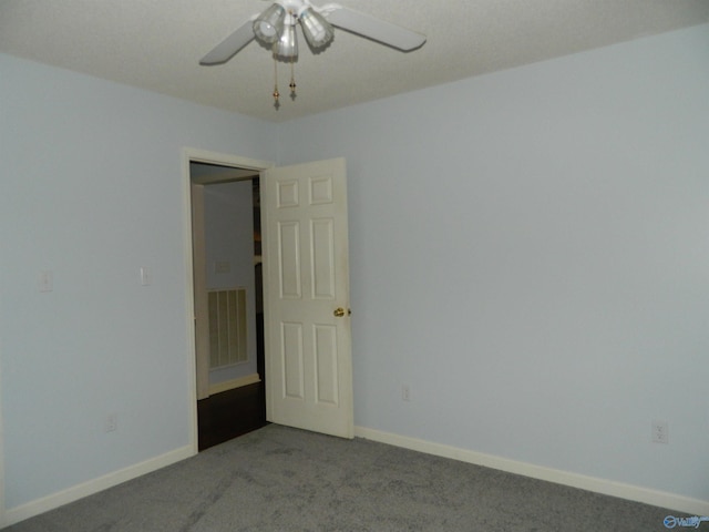 carpeted spare room featuring ceiling fan, visible vents, and baseboards