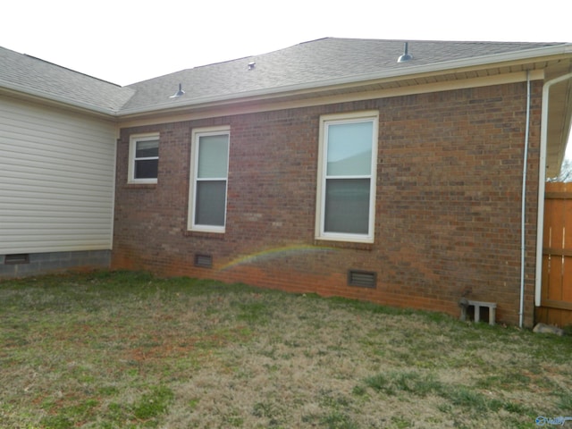 view of home's exterior featuring brick siding, crawl space, a shingled roof, and a lawn