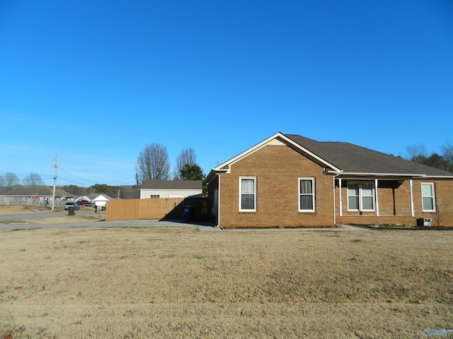 view of home's exterior featuring fence, a lawn, and brick siding