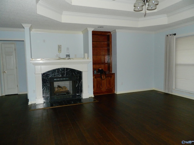 unfurnished living room with a raised ceiling, ornamental molding, a high end fireplace, baseboards, and hardwood / wood-style flooring