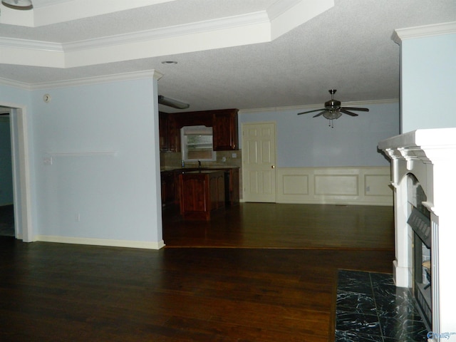 unfurnished living room with a ceiling fan, a fireplace with flush hearth, dark wood-style flooring, crown molding, and a sink