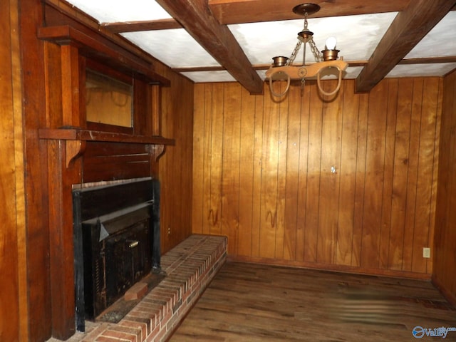 living room featuring dark wood-type flooring, wood walls, beamed ceiling, and a fireplace