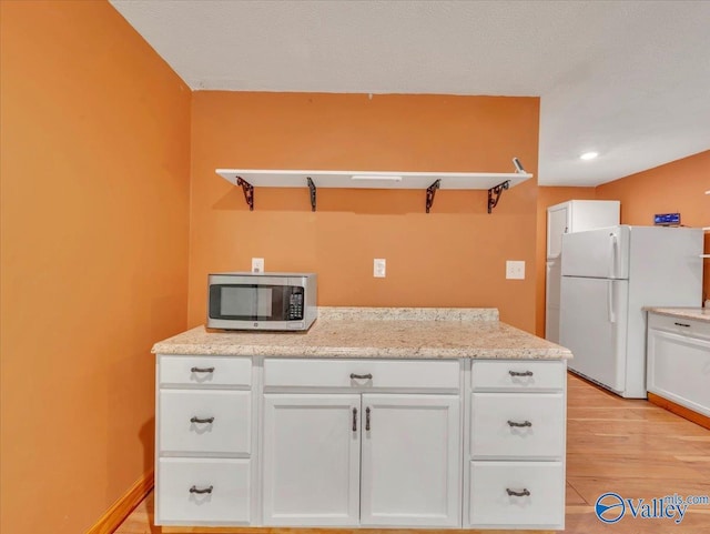 1228 Matt Morrow Rd, Arab, AL 35016 - kitchen featuring stainless steel microwave, freestanding refrigerator, white cabinets, and light wood-style flooring