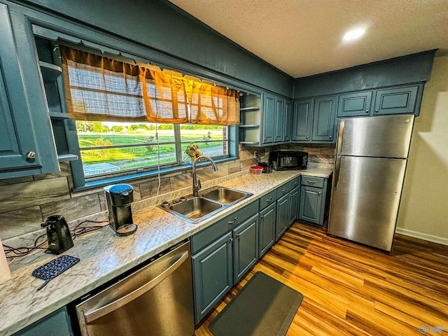 kitchen with stainless steel appliances, wood finished floors, a sink, backsplash, and open shelves