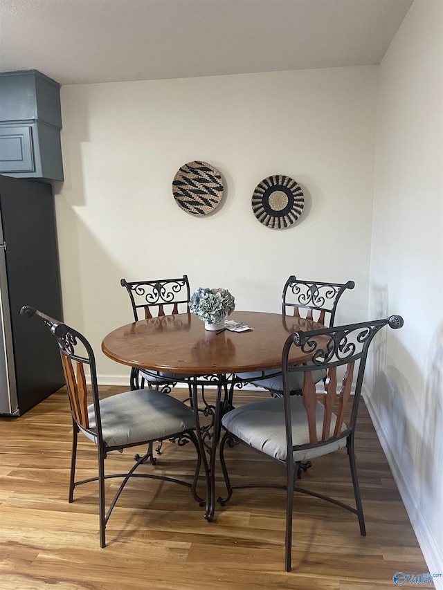 dining space featuring light wood-type flooring and baseboards