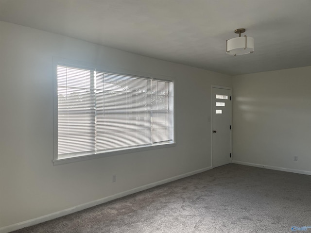 carpeted spare room with baseboards and a wealth of natural light