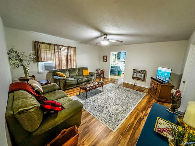 living area featuring ceiling fan, wood finished floors, heating unit, a textured ceiling, and cooling unit