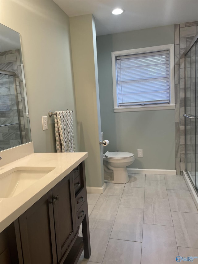 bathroom featuring toilet, vanity, baseboards, tile patterned floors, and a stall shower