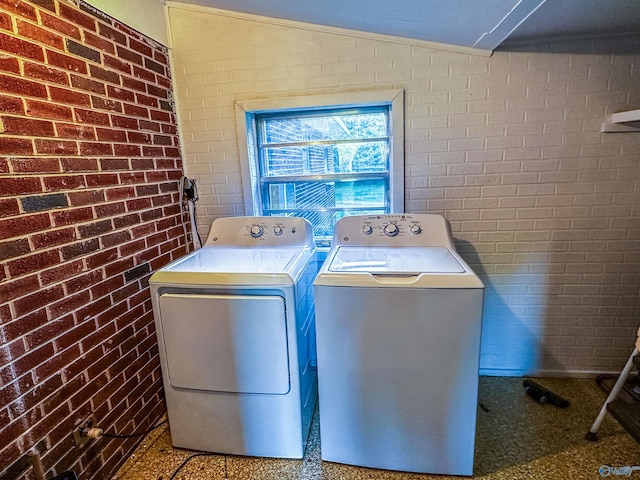 laundry area featuring laundry area, brick wall, and separate washer and dryer