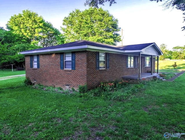 view of side of home featuring a yard, brick siding, and crawl space