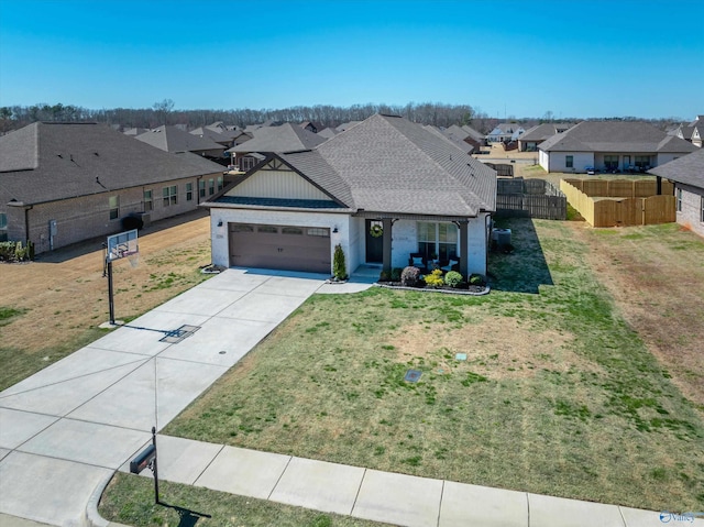 view of front of home with a front lawn, concrete driveway, fence, and a residential view