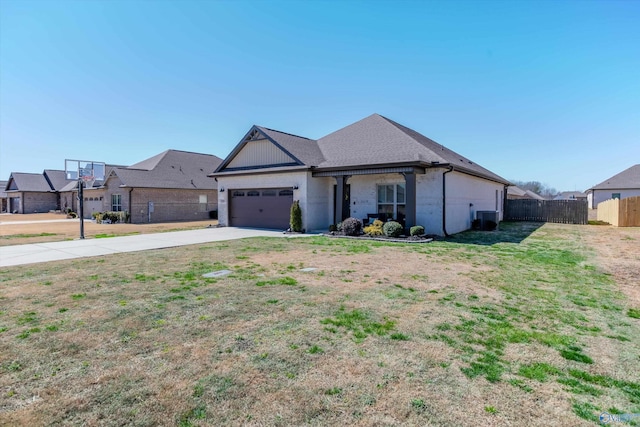 view of front of house with central air condition unit, fence, concrete driveway, a front yard, and a garage