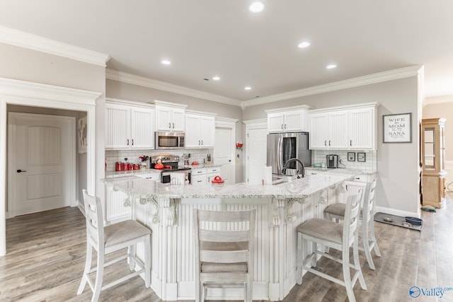 14537 Willow Bend Dr, Athens, AL 35613 - kitchen featuring appliances with stainless steel finishes, white cabinets, tasteful backsplash, light wood-style flooring, and crown molding
