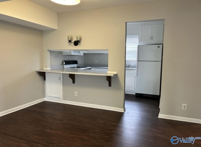 kitchen featuring electric range, baseboards, a kitchen breakfast bar, and freestanding refrigerator