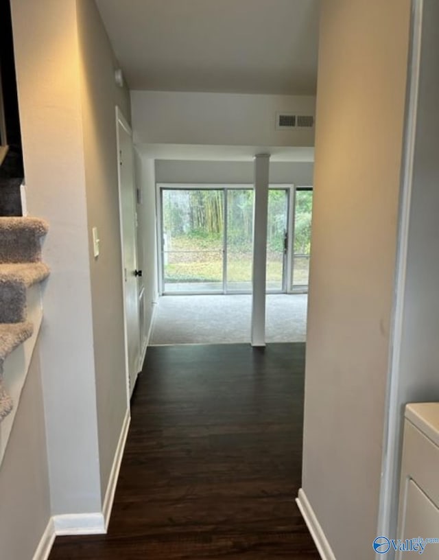 hallway featuring visible vents, dark wood finished floors, and baseboards