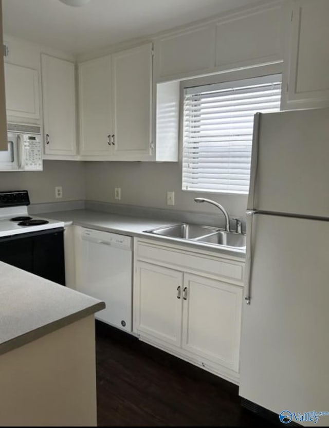 kitchen featuring light countertops, white appliances, a sink, and white cabinets