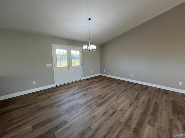 unfurnished dining area featuring lofted ceiling, dark hardwood / wood-style floors, and an inviting chandelier