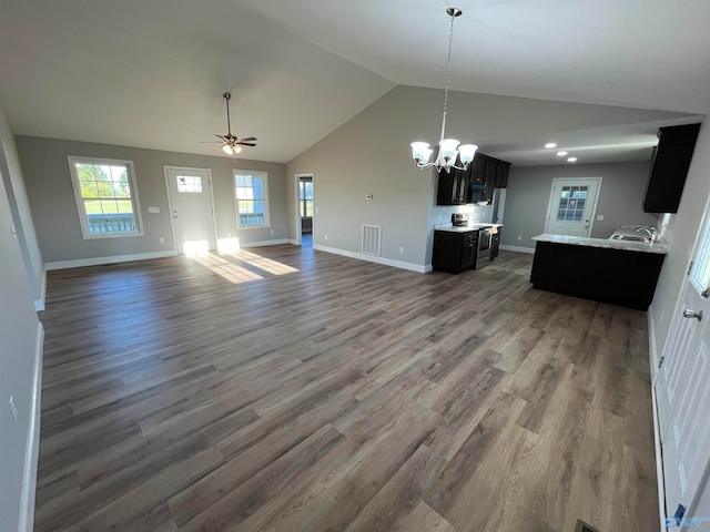 kitchen with lofted ceiling, dark hardwood / wood-style flooring, ceiling fan with notable chandelier, and hanging light fixtures