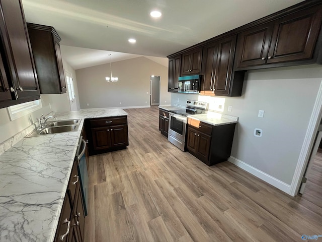 kitchen featuring appliances with stainless steel finishes, sink, vaulted ceiling, decorative light fixtures, and light hardwood / wood-style flooring