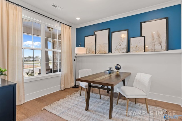 dining room with crown molding and light wood-type flooring