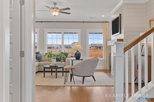 sitting room with wood-type flooring, ceiling fan, and crown molding