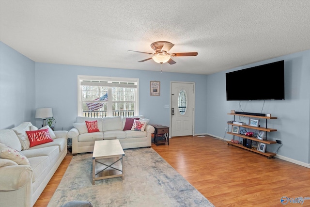 living room featuring ceiling fan, a textured ceiling, and light hardwood / wood-style floors