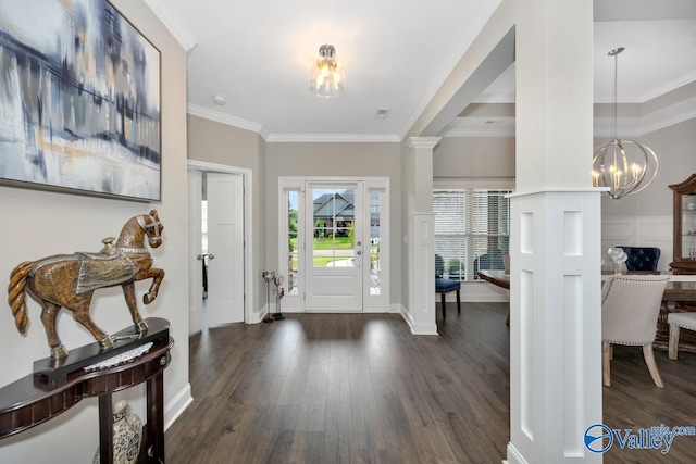 entrance foyer with crown molding, dark hardwood / wood-style floors, an inviting chandelier, and decorative columns