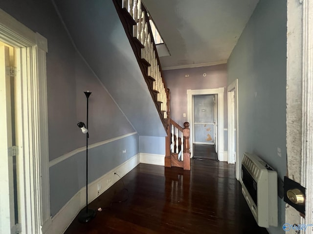 hallway with dark hardwood / wood-style flooring, ornamental molding, and heating unit