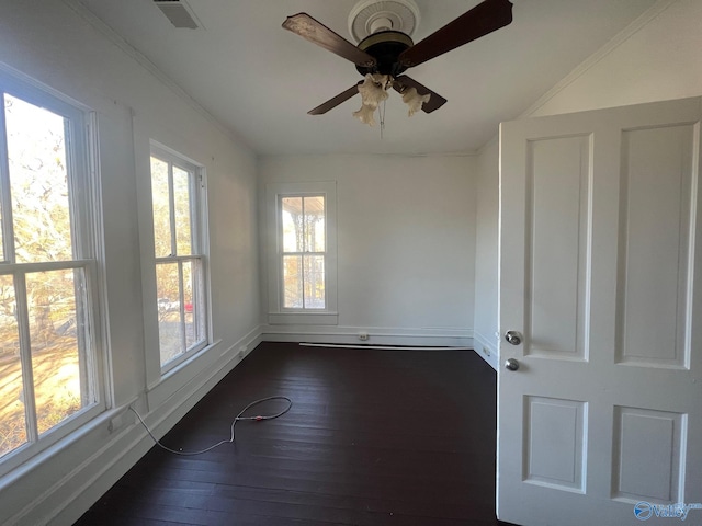 empty room featuring ceiling fan, plenty of natural light, dark wood-type flooring, and ornamental molding