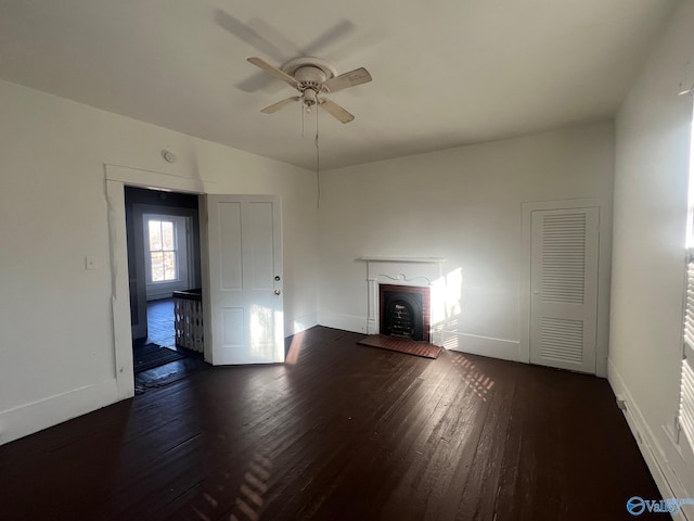 unfurnished living room with ceiling fan, dark hardwood / wood-style flooring, and a brick fireplace