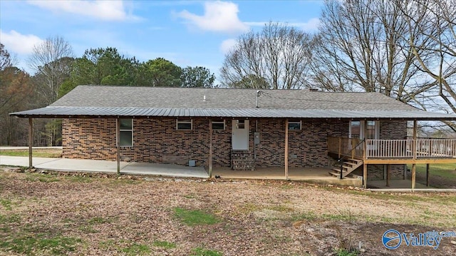 rear view of house with a wooden deck and a patio area