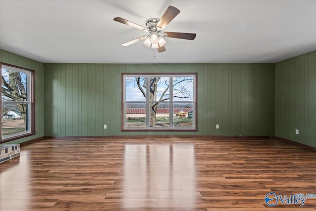 empty room featuring dark wood-type flooring, ceiling fan, and plenty of natural light