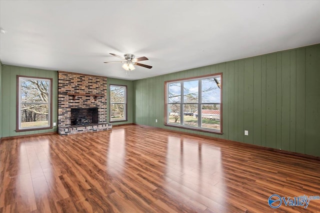 unfurnished living room featuring hardwood / wood-style flooring, ceiling fan, and a fireplace