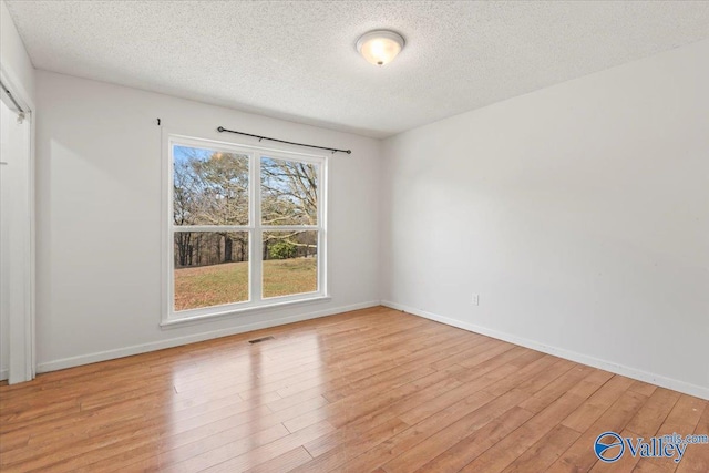 spare room featuring light hardwood / wood-style flooring and a textured ceiling