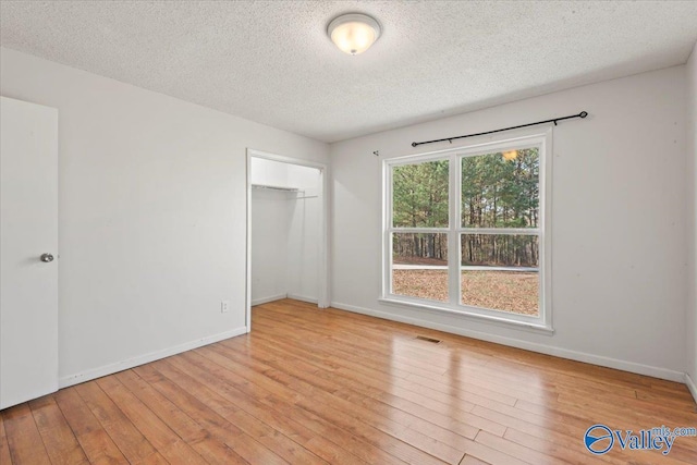 unfurnished bedroom with a closet, light hardwood / wood-style flooring, and a textured ceiling