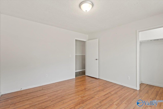 unfurnished bedroom featuring a closet, a textured ceiling, and light wood-type flooring