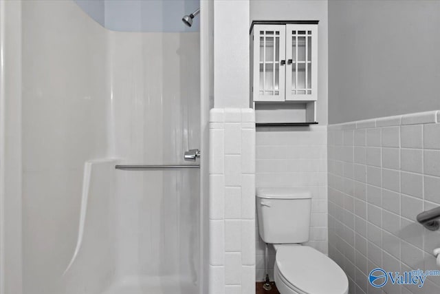 bathroom featuring toilet, tile walls, and a shower