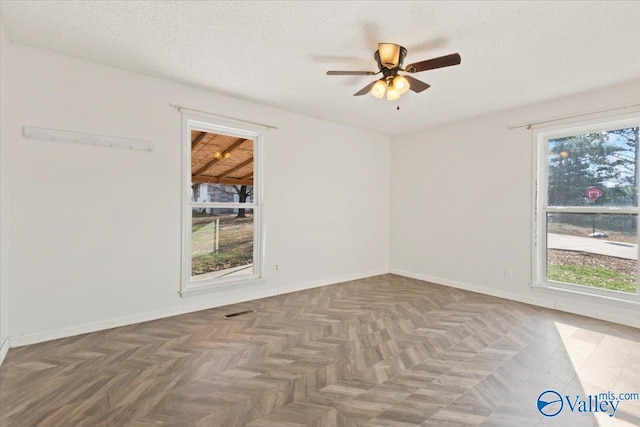 spare room featuring dark parquet flooring, ceiling fan, and a textured ceiling