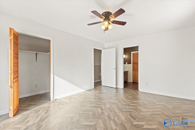 unfurnished bedroom with parquet flooring, connected bathroom, ceiling fan, a textured ceiling, and a closet