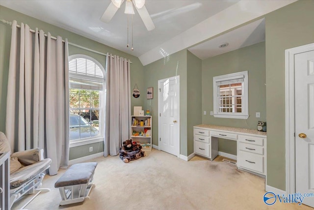 office featuring vaulted ceiling, ceiling fan, built in desk, and light colored carpet