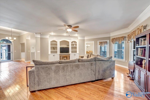 living room featuring ceiling fan with notable chandelier, ornamental molding, and light wood-type flooring