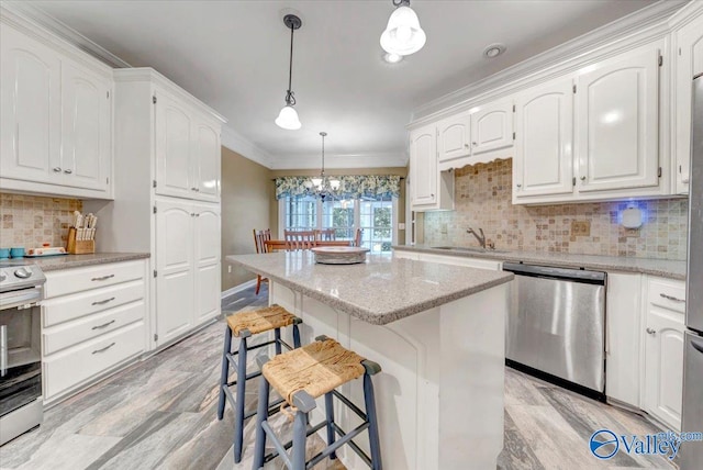 kitchen with decorative light fixtures, white cabinetry, appliances with stainless steel finishes, crown molding, and a kitchen bar