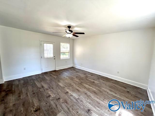 spare room with a ceiling fan, dark wood-style floors, and baseboards