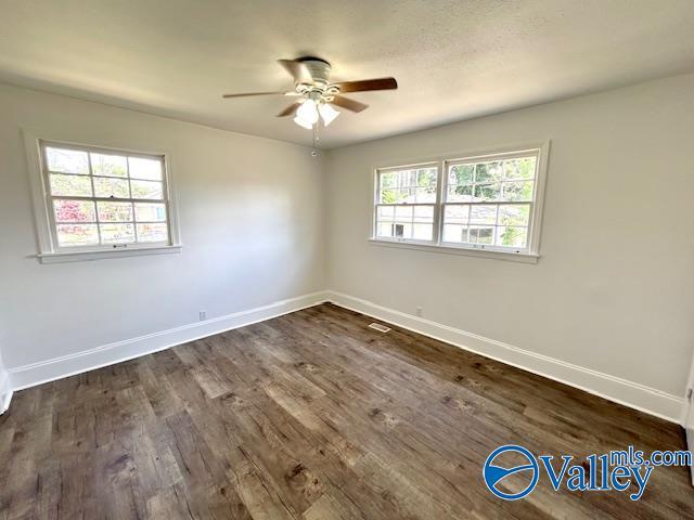 unfurnished room with dark wood-type flooring, ceiling fan, and baseboards