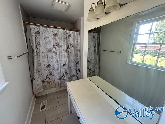 full bath with tile patterned floors, baseboards, a shower with shower curtain, and a healthy amount of sunlight
