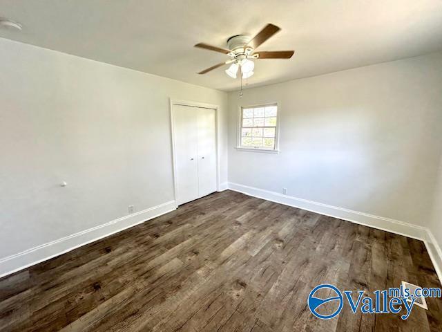 unfurnished bedroom featuring dark wood-style flooring, ceiling fan, and baseboards